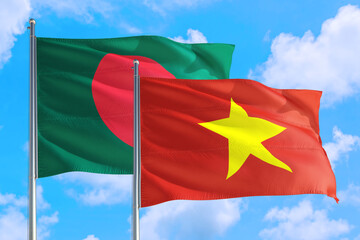 Vietnam and Bangladesh national flag waving in the windy deep blue sky. Diplomacy and international relations concept.