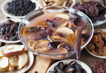Kissel with dried fruits surrounded by dried fruits on plates on a wooden background. Healthy natural homemade dessert. Home preparation of dried fruits.