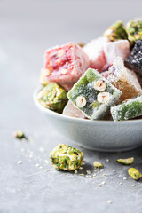Baklava, halva, rahat lokum, sherbet, nuts, pistachios, in bowl on grey background. Assorted traditional eastern desserts, arabian sweets, turkish delight.