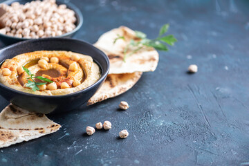 Chickpeas hummus, olive oil, raw chickpeas, smoked paprika, pita on dark background. Middle eastern, jewish cuisine or arabic dishes. Top view. Copy space. Snacks set. Vegan, vegetarian food concept
