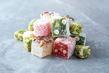 Traditional turkish delight on grey background. Arab dessert, baklava, halva, rahat lokum, sherbet, nuts, pistachios in bowl on grey background
