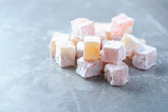Turkish delight - rahat lokum or lokum with sugar powder on grey background. Traditional eastern cuisine. Traditional middle eastern sweets. Jewish, turkish, arabic national dessert. Turkish delight