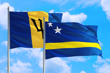 Curacao and Barbados national flag waving in the windy deep blue sky. Diplomacy and international relations concept.