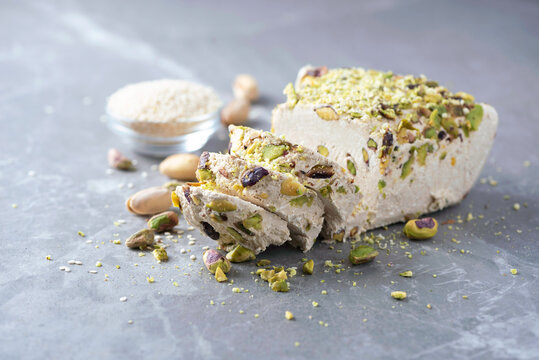 Sesame halva with pistachios on grey background. Top view. Copy space. Traditional middle eastern sweets. Jewish, turkish, arabic national dessert. Turkish delight