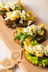 Toasted sandwiches with brie cheese, baked pumpkin and salad, arugula and mozzarella, delicious vegetable snacks on a wooden board