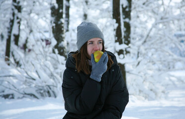Fototapeta na wymiar Young woman walks in the winter forest. Girl eating an apple