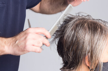 Fototapeta premium Hairdresser trimming brown hair with scissors