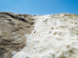 Background of pile of natural salt collected in saline on volcanic rock under blue sky. Ecosystem...