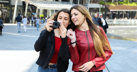 Two girls shooting pictures with a digital camera outdoor in the city