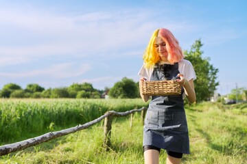 Fototapeta premium Teenage girl with basket of fresh strawberries walking along country road