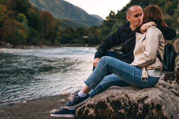 Young couple kissing and hugging near the lake in the mountains.