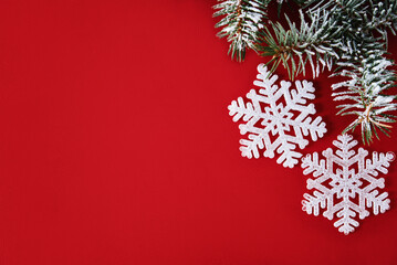 Christmas composition with white snowflake and christmas tree branch on red background, top view