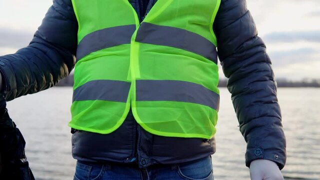 A volunteer on a city beach found a used condom and puts it in a garbage bag. Environmental pollution
