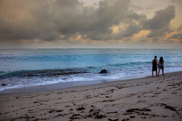 Naklejka premium entardecer em uma praia com um casal passeando de mãos dadas ao fundo