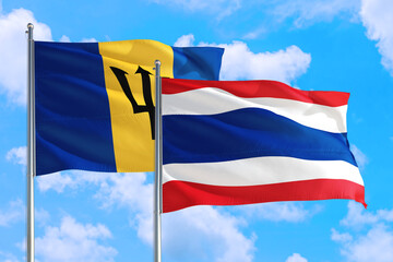 Thailand and Barbados national flag waving in the windy deep blue sky. Diplomacy and international relations concept.