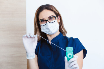 Latin woman dentist with floss for health care in consulting room in Mexico