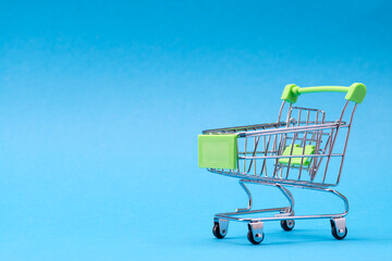 Tiny shopping cart on the blue background with space for text