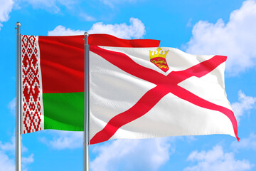 Fototapeta na wymiar Jersey and Belarus national flag waving in the windy deep blue sky. Diplomacy and international relations concept.