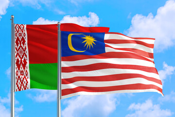 Malaysia and Belarus national flag waving in the windy deep blue sky. Diplomacy and international relations concept.