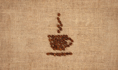 Conceptual artistic pattern of a cup of coffee made from coffee beans on rustic burlap background