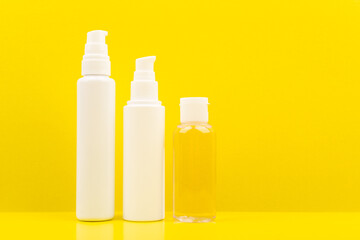 Minimalistic still life with cleaning foam, face cream and skin lotion on bright yellow background