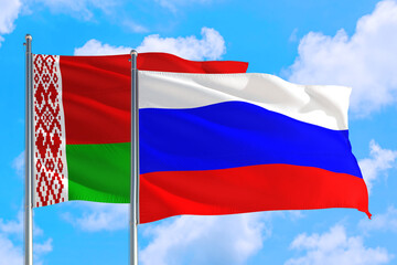 Russia and Belarus national flag waving in the windy deep blue sky. Diplomacy and international relations concept.