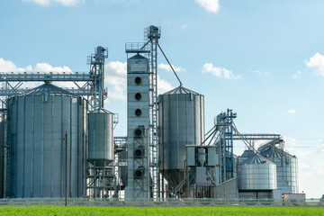 silver silos on agro manufacturing plant for processing drying cleaning and storage of agricultural products, flour, cereals and grain. Large iron barrels of grain. Granary elevator