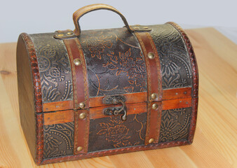 close-up of a closed brown chest with an ornament on a wooden table