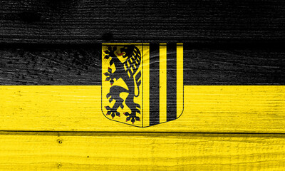 dresden flag painted on old wood plank background. Brushed natural light knotted wooden board...