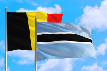 Botswana and Belgium national flag waving in the windy deep blue sky. Diplomacy and international relations concept.