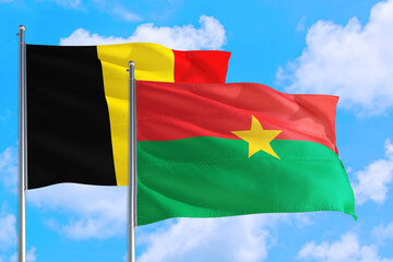 Burkina Faso and Belgium national flag waving in the windy deep blue sky. Diplomacy and international relations concept.
