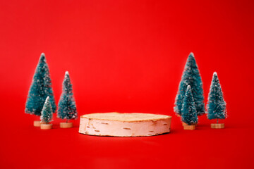 Mock up with wooden podium from a circle of wood on trendy red background with christmas decoration tree. Place for christmas product presentation