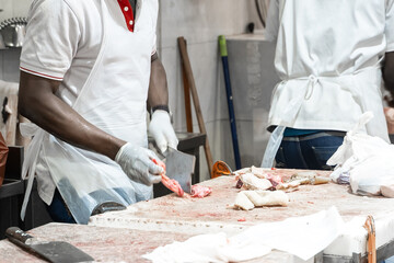 African american butcher cutting meat at counter in butchery. A man cook cut fresh bacon meat
