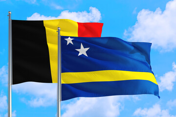 Curacao and Belgium national flag waving in the windy deep blue sky. Diplomacy and international relations concept.
