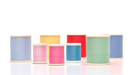 Various pastel sewing thread spools on white