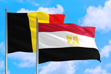 Egypt and Belgium national flag waving in the windy deep blue sky. Diplomacy and international relations concept.