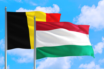 Hungary and Belgium national flag waving in the windy deep blue sky. Diplomacy and international relations concept.