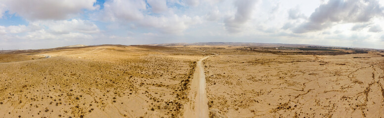 Fototapeta na wymiar Wide panoramic view from the sky to dirt road over desert Negew