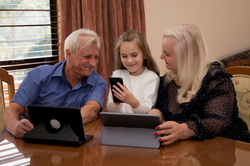 A little girl makes purchases on the Internet with her grandfather and grandmother.