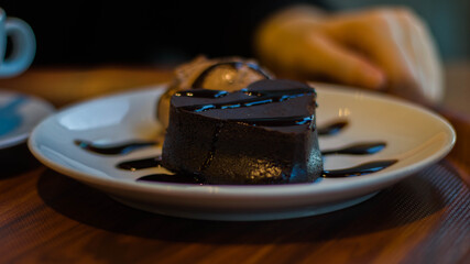 A heart-shaped chocolate cake on a plate served with an ice-cream