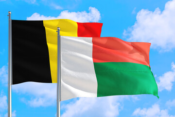 Madagascar and Belgium national flag waving in the windy deep blue sky. Diplomacy and international relations concept.