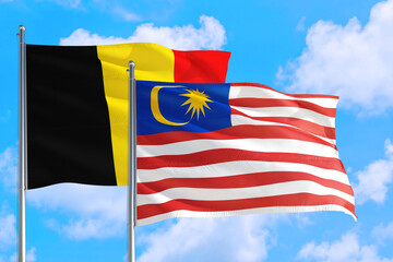 Malaysia and Belgium national flag waving in the windy deep blue sky. Diplomacy and international relations concept.