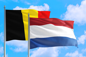 Netherlands and Belgium national flag waving in the windy deep blue sky. Diplomacy and...