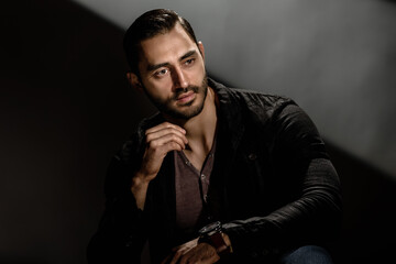 Portrait of stylish handsome minded brunet posing on studio background