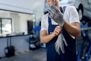 Fototapeta na wymiar Unrecognizable mechanic using working gloves at auto repair shop.