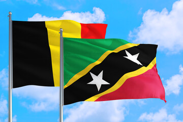 Saint Kitts And Nevis and Belgium national flag waving in the windy deep blue sky. Diplomacy and international relations concept.