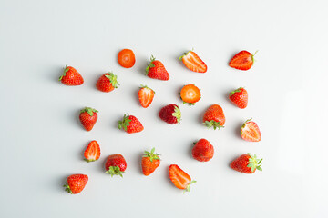 Ripe whole and sliced strawberry on light surface