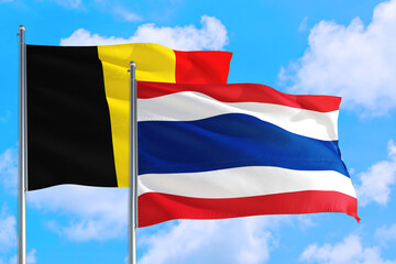 Thailand and Belgium national flag waving in the windy deep blue sky. Diplomacy and international relations concept.