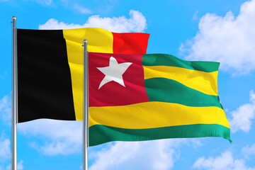 Togo and Belgium national flag waving in the windy deep blue sky. Diplomacy and international relations concept.