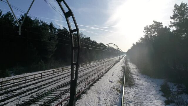 Low altitude aerial view of electric railway overhead lines and classic concrete arches official monument located over forest train track showing snowy scenery and trees on both side 4k quality